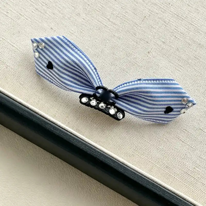 Blue and white striped bow hair clip on a textured surface