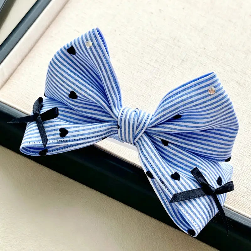 Blue and white striped bow with black accents on a neutral background